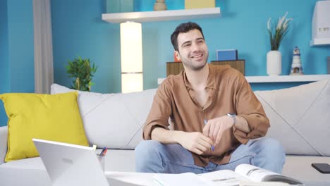 Young-man-sitting-alone-at-home-thinking-about-happy-moments-and-smiling.